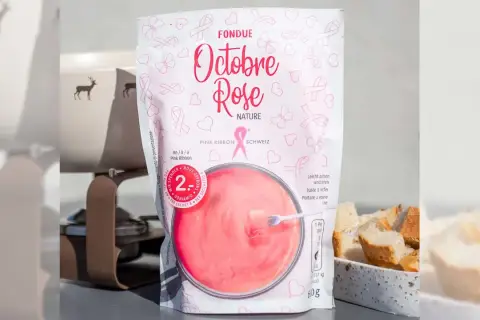 Un sachet de fondue au rosé "Octobre Rose" aux motifs de rubans roses, prêt à être dégusté avec du pain.