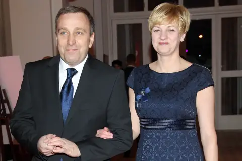 Cezary Grabarczyk z żoną, w eleganckich strojach. Może rozmawiają o swoich dzieciach i ich przyszłości.