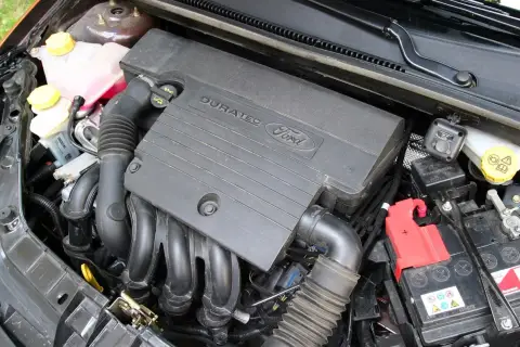 Silnik Duratec w Fordzie Fiesta Mk6. Widoczny jest czarny plastikowy kolektor, przewody i akumulator.
