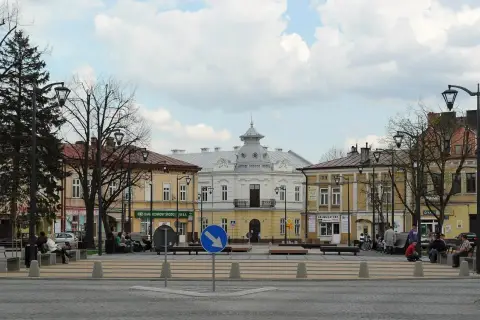 Rynek w Mielcu z kamienicami i ludźmi odpoczywającymi na ławkach. Idealne miejsce na mieleckie atrakcje na weekend.
