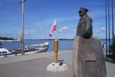 Pomnik upamiętniający zaślubiny Polski z morzem. Obok żaglowiec i polska flaga.