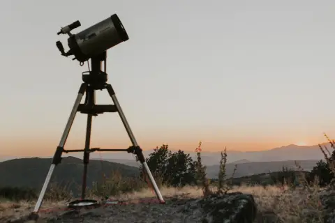 Telescopi preparat per a un sopar amb estrelles. El cel s'enfosqueix sobre les muntanyes, prometent una nit d'observació celestial.