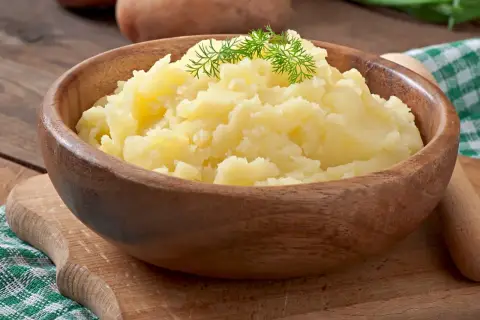 Puszyste puree ziemniaczane w drewnianej misce, ozdobione koperkiem. Idealne jako alternatywa dla masła, gdy zastanawiasz się, co dodać do ziemniaków.