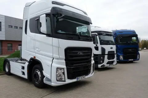 Trzy ciężarówki Ford F650 stoją obok siebie. Biała, biała i niebieska ciężarówka.