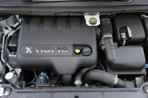 Silnik Peugeot 307 2.0 HDi 16V. Widoczny czarny plastikowy kolektor, zbiorniczek płynu hamulcowego i elementy układu dolotowego.
