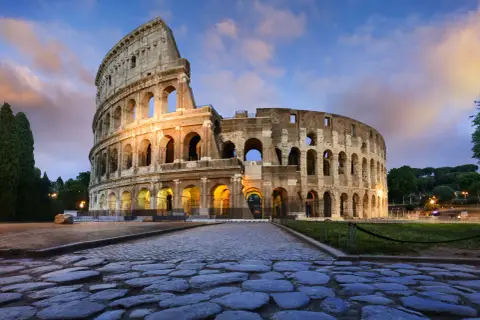 Il Colosseo, uno dei più maestosi monumenti di Roma, illuminato al tramonto con un cielo suggestivo.