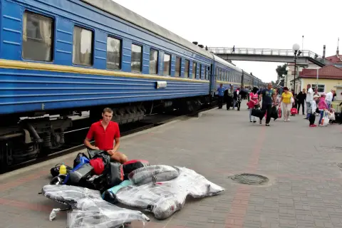 Młody mężczyzna z bagażami na peronie, przygotowuje się do podróży na wjazd na Ukrainę w czasie wojny.