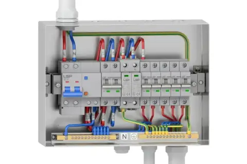 Wnętrze skrzynki elektrycznej z wyłącznikiem głównym 32A i kilkoma mniejszymi zabezpieczeniami nadprądowymi, okablowanie L, N, PE.
