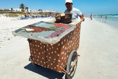 Sprzedawca na plaży w Tunezji oferuje słodycze. Może to być okazja do wymiany drobnych na pyszności, bo tunezja waluta to dinar.