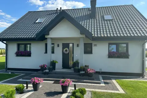 Nowoczesny dom Kamilek 100m2 z pięknymi kwiatami w donicach i skrzynkach.