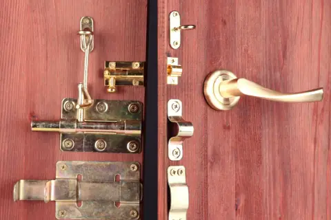 Detalle de varios tipos de pestillos para puertas de madera, con acabados dorados y plateados, incluyendo manijas.