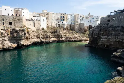 Un estany gento con aguas cristalinas rodea un pueblo blanco construido sobre acantilados rocosos.