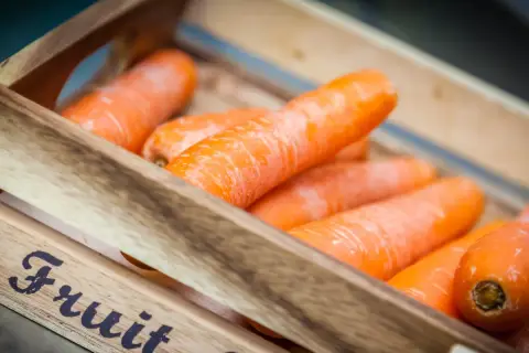 Pomarańczowa marchewka w drewnianej skrzynce, gotowa na zdrowy posiłek.