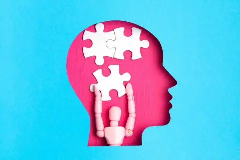 Drewniany ludzik układa puzzle w głowie, symbolizując otwarty umysł i proces myślowy.