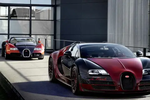 Dwa Bugatti Veyron w kolorach czarnym i czerwonym przed nowoczesnym budynkiem.