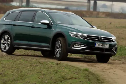 Zielony Passat Alltrack pokonuje piaszczystą drogę wśród traw.