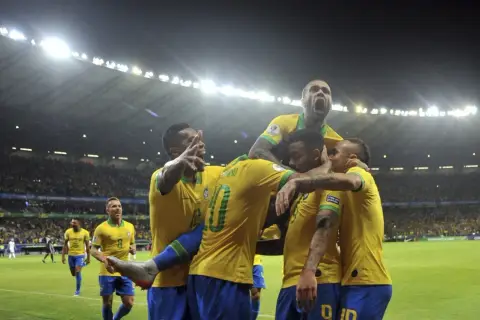 Piłkarze Brazylii świętują zwycięstwo nad Argentyną. Stadion wypełniony kibicami, nocne światła oświetlają murawę.
