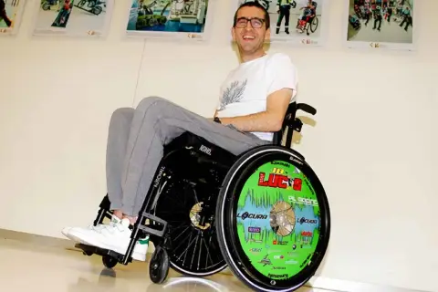 Lucas de Ulacia sonríe en su silla de ruedas, con la rueda decorada con "¡Lucas!".