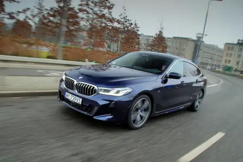 Granatowe BMW 640i sunie po miejskiej drodze, ukazując swoje eleganckie linie i sportowy charakter.
