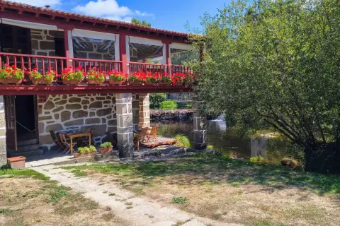 Casa rural con balcón florido y río. Un lugar idílico para descubrir qué ver en Allariz y disfrutar de la naturaleza.