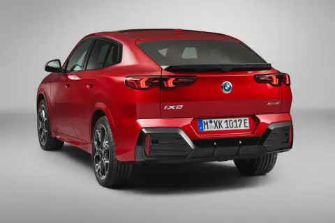 Czerwone BMW iX2 z napisem "XDrive30" na klapie bagażnika, z tyłu widoczne są lampy LED i tablica rejestracyjna.