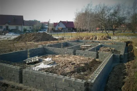 Budowa fundamentów domu w trakcie. Widać zbrojenie i bloczki betonowe, przygotowywane pod izolację poziomą fundamentów.