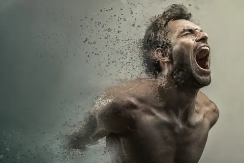 Uomo che urla, dissolvendosi in particelle, con un'espressione di profonda paura di impazzire.