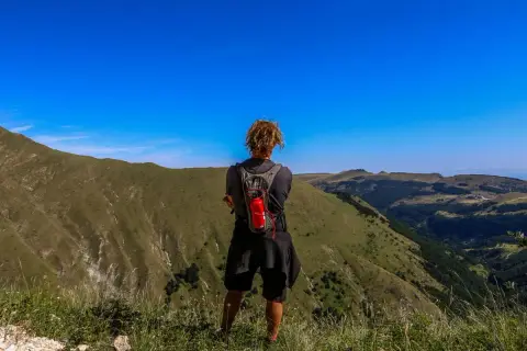 Persona con zaino ammira il panorama durante un trekking di 3 giorni nei Monti Sibillini.