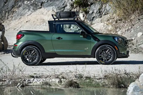 Zielony mini paceman z bagażnikiem dachowym i zapasowym kołem, gotowy na przygodę w terenie.