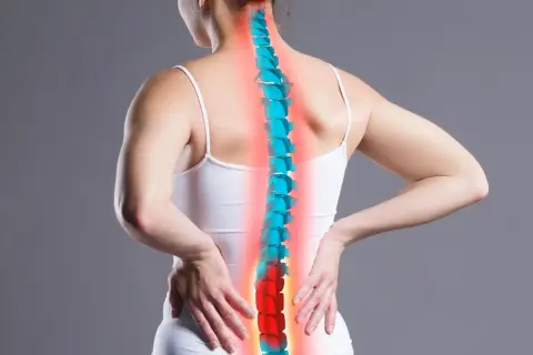 Kobieta odczuwa ból pleców, który może być jednym z objawów osteoporozy. Kręgosłup zaznaczony na czerwono.