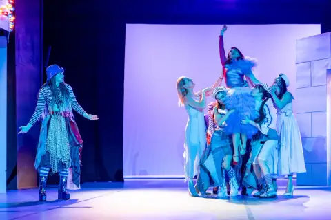 Na scenie Teatru Miejskiego w Gdyni trwa spektakl. Grupa artystów w barwnych strojach tworzy żywą piramidę, a jedna z postaci wznosi się na szczyt.