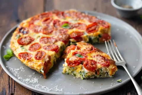 Pyszna pizza z cukinii z pomidorkami i bazylią na talerzu, gotowa do podania.