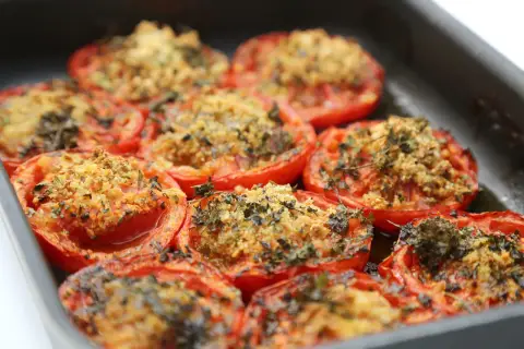 Tomates au barbecue, coupées en deux et garnies d'une chapelure aux herbes, cuites dans un plat.