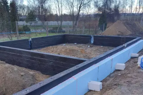 Budowa domu w toku. Widać zbrojenie i izolację fundamentów.