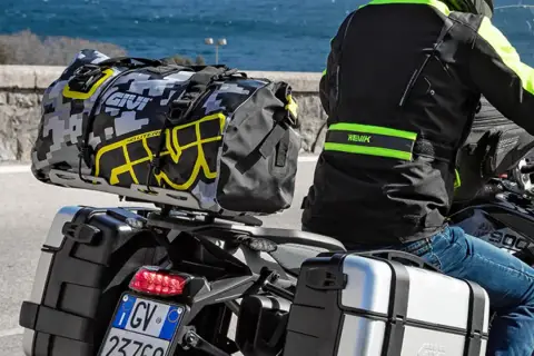 Motociclista con equipaje en maletas laterales y bolsa trasera. Es correcto transportar el equipaje en maletas laterales para viajes largos.