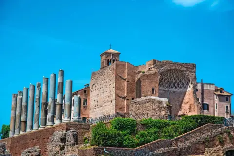 Vestiges de la Domus Aurea, avec ses colonnes antiques et ses ruines de briques sous un ciel bleu éclatant.