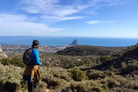 Senderista contempla el Peñón de Ifach y la costa desde una de las rutas de Calpe.