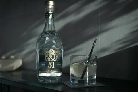 Butelka Purity Vodka i szklanka z drinkiem. Wódka, okowita i bimber – definicje prawne.