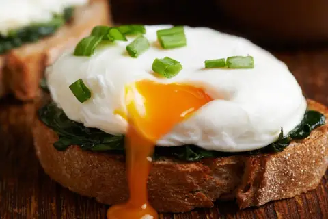 Jajko sadzone na grzance ze szpinakiem, z płynnym żółtkiem. Dwa jajka sadzone mają ok. 140 kcal.
