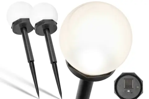 Dwie białe lampy solarne w kształcie kuli z czarnymi tyczkami. Na dole jednej z lamp widać panel solarny, który ładuje się od słońca, a nie od żarówki.