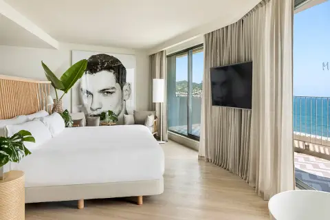Habitación moderna en el hotel Terramar Sitges con cama king, arte de gran tamaño y vistas al mar.