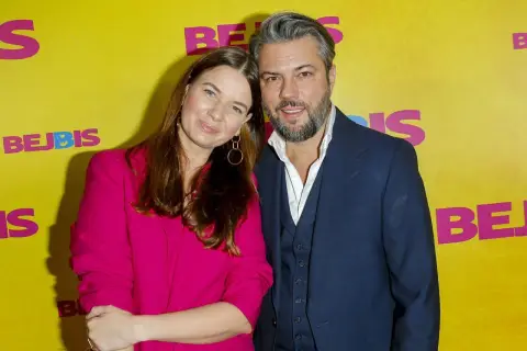 Karolina Malinowska Janiak i jej partner pozują na tle żółtej ścianki z napisem "BEJBIS".
