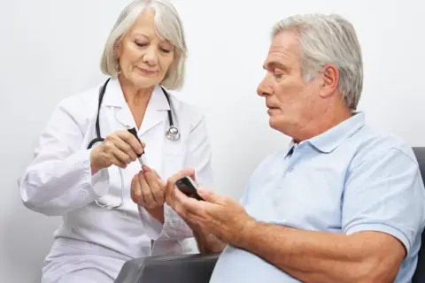 Diabetolog bada poziom cukru we krwi pacjenta.