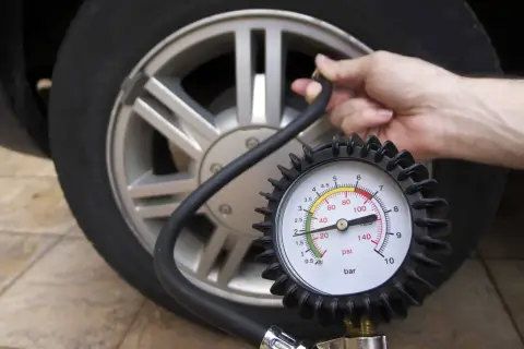 Manometro collegato a una ruota d'auto, dove è scritta la pressione dei pneumatici.