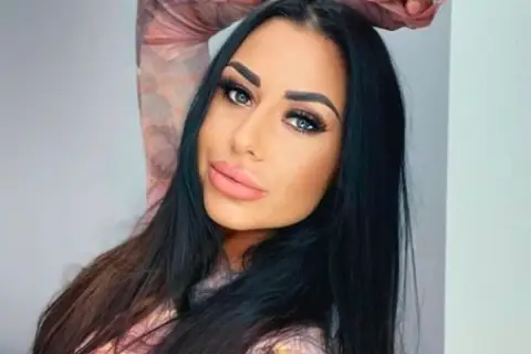 Stella z Love Island, z długimi czarnymi włosami i wyrazistym makijażem, pozuje do zdjęcia.