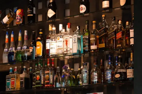 Na półkach barowych stoją butelki alkoholi, w tym kilka butelek tequili, idealnych do przygotowania pysznej margarity.