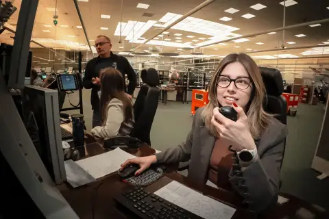 Kontroler ruchu lotniczego w akcji, monitoruje przestrzeń powietrzną i komunikuje się przez radio.