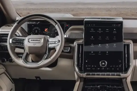 Wnętrze GMC Yukon XL z dużym ekranem dotykowym, kierownicą Denali i cyfrowymi wskaźnikami.