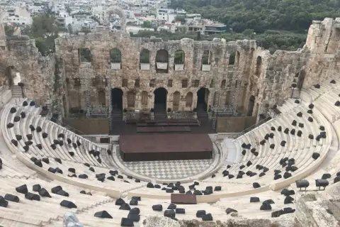Starożytny Odeon Heroda Attyka w Atenach, z kamiennymi siedzeniami i sceną, w tle widać miasto.
