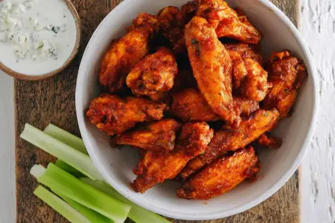 Chrupiące skrzydełka z airfryer w misce, obok sosu blue cheese i łodyg selera. Idealna przekąska!